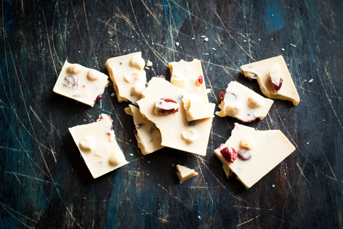 A creamy and smooth vegan white chocolate bar, displayed with cocoa butter and vanilla beans, highlighting the plant-based ingredients that make it dairy-free.