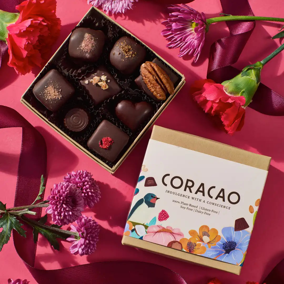 Box of Coracao chocolates with a card on a pink background